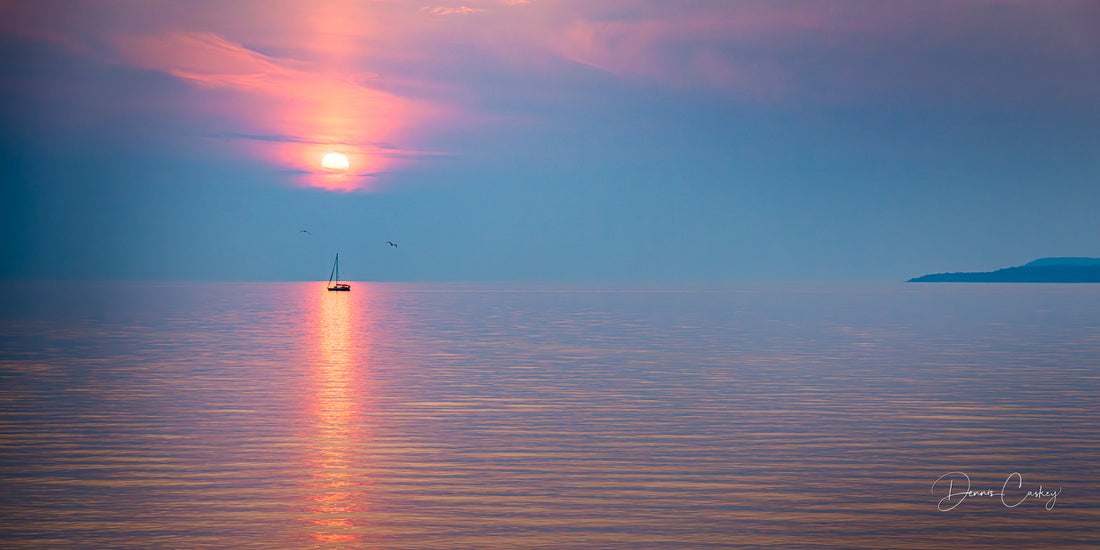 A minimalist fine art photograph of calm waters under a soft, cloudy sky, reflecting tranquility and simplicity in nature.