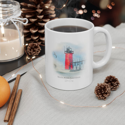 South Haven Lighthouse ceramic mug by Dennis Caskey sitting on a table with coffee