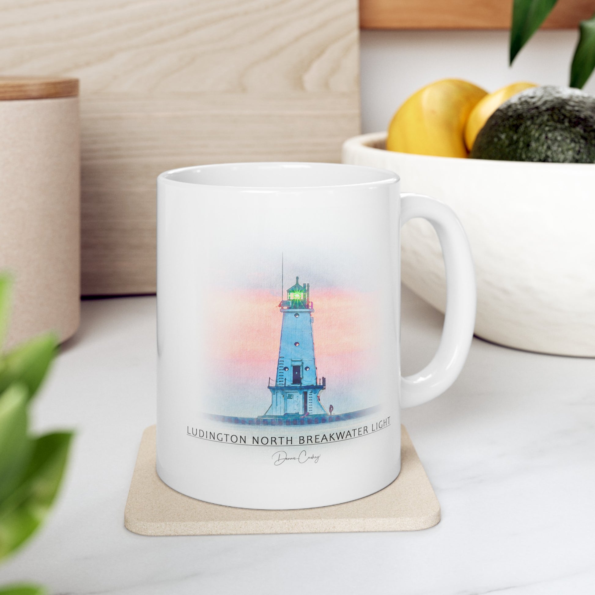 South Haven Lighthouse ceramic mug by Dennis Caskey sitting on a table with coffee