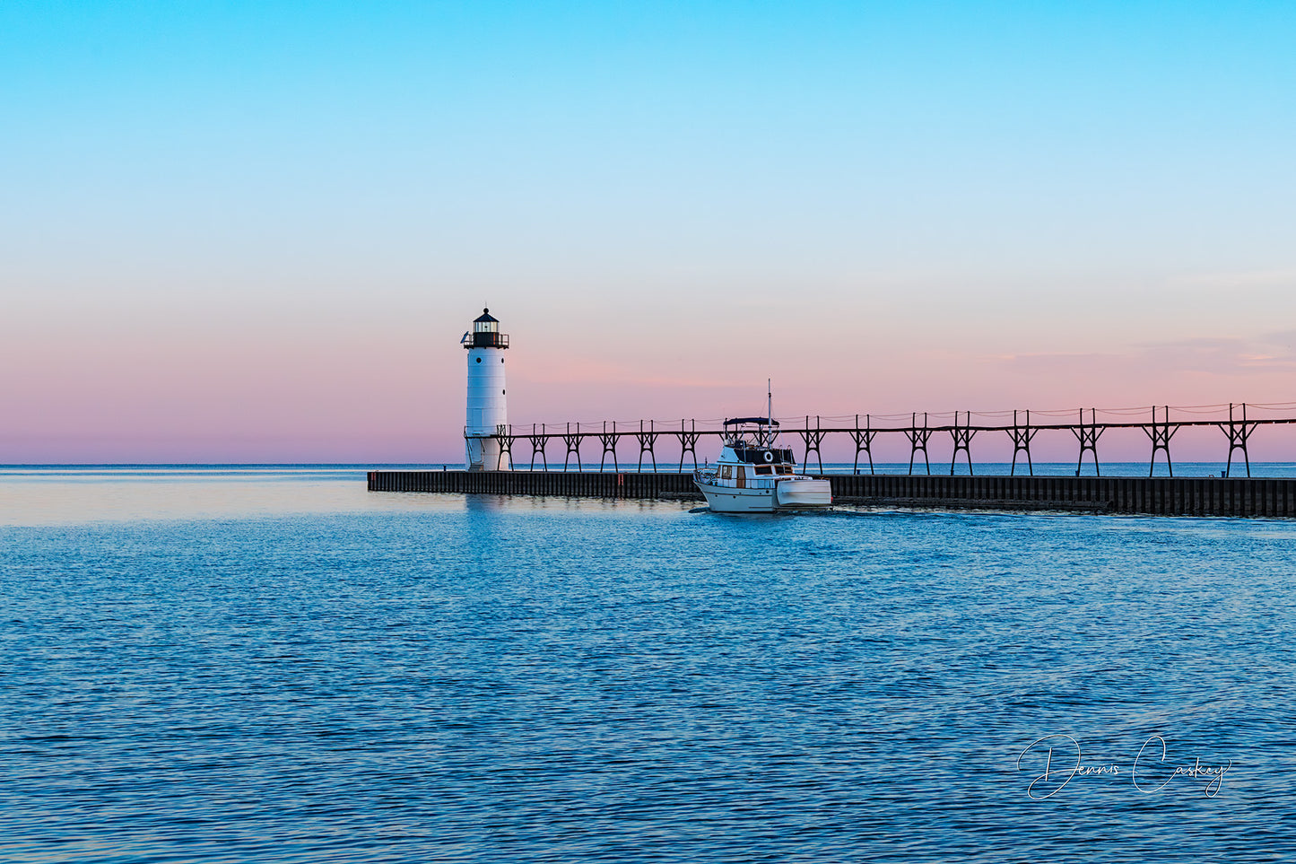 Fishing boat traveling down a channel next to Manistee lighthouse stock photo by Dennis Caskey